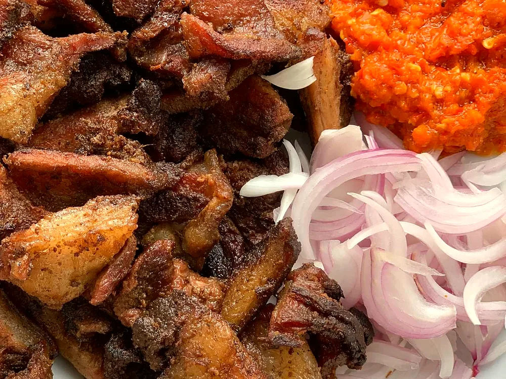 Spiced beef suya skewers grilling over charcoal